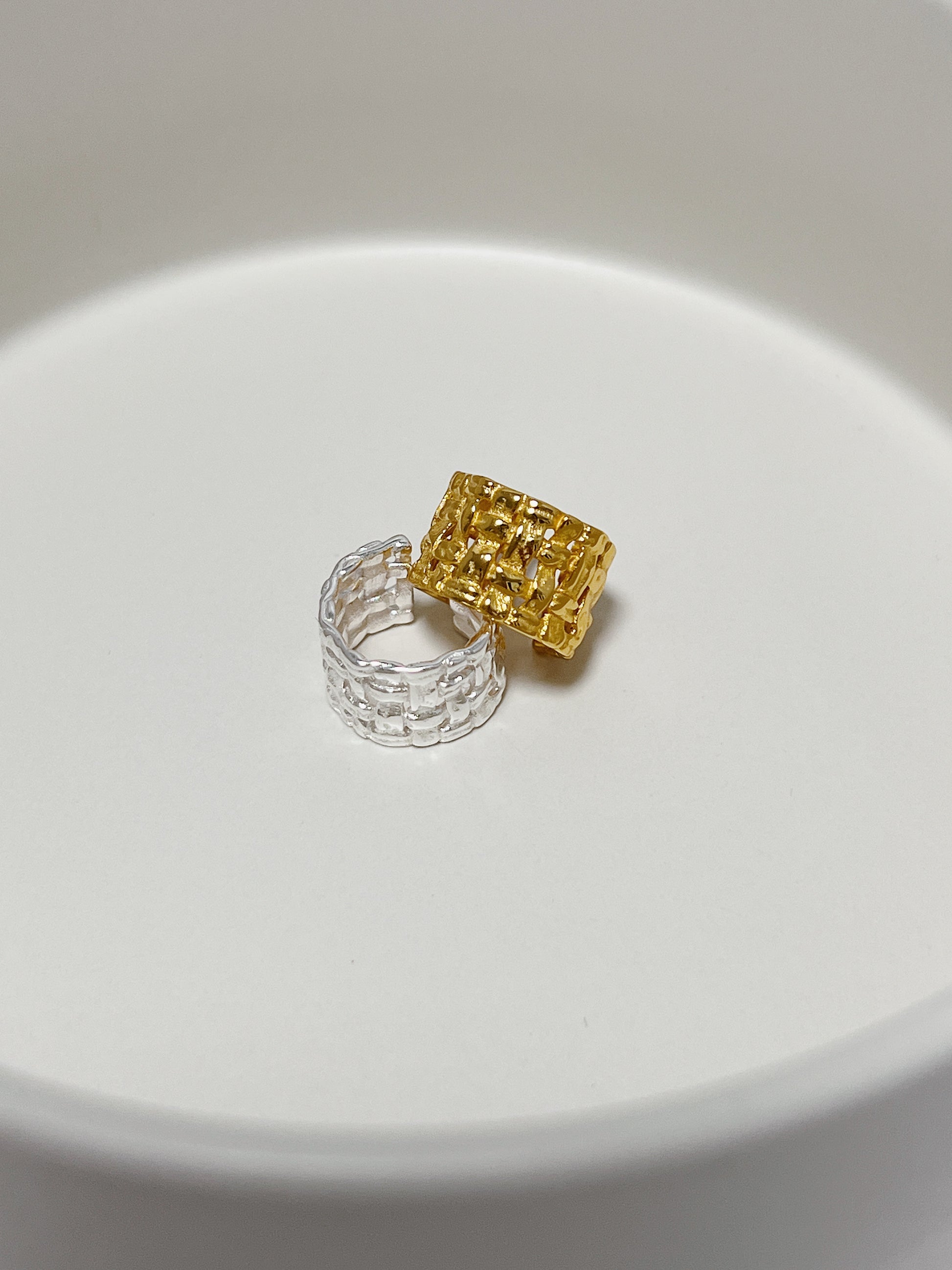 The Carmela Woven Cuff stacking together on a minimalist background to show its bold sculptural profile.