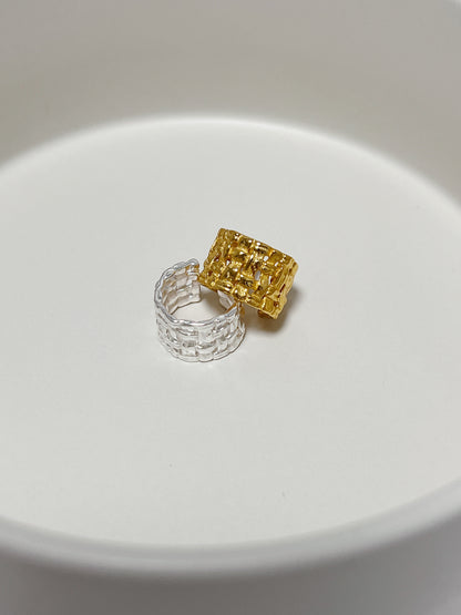 The Carmela Woven Cuff stacking together on a minimalist background to show its bold sculptural profile.