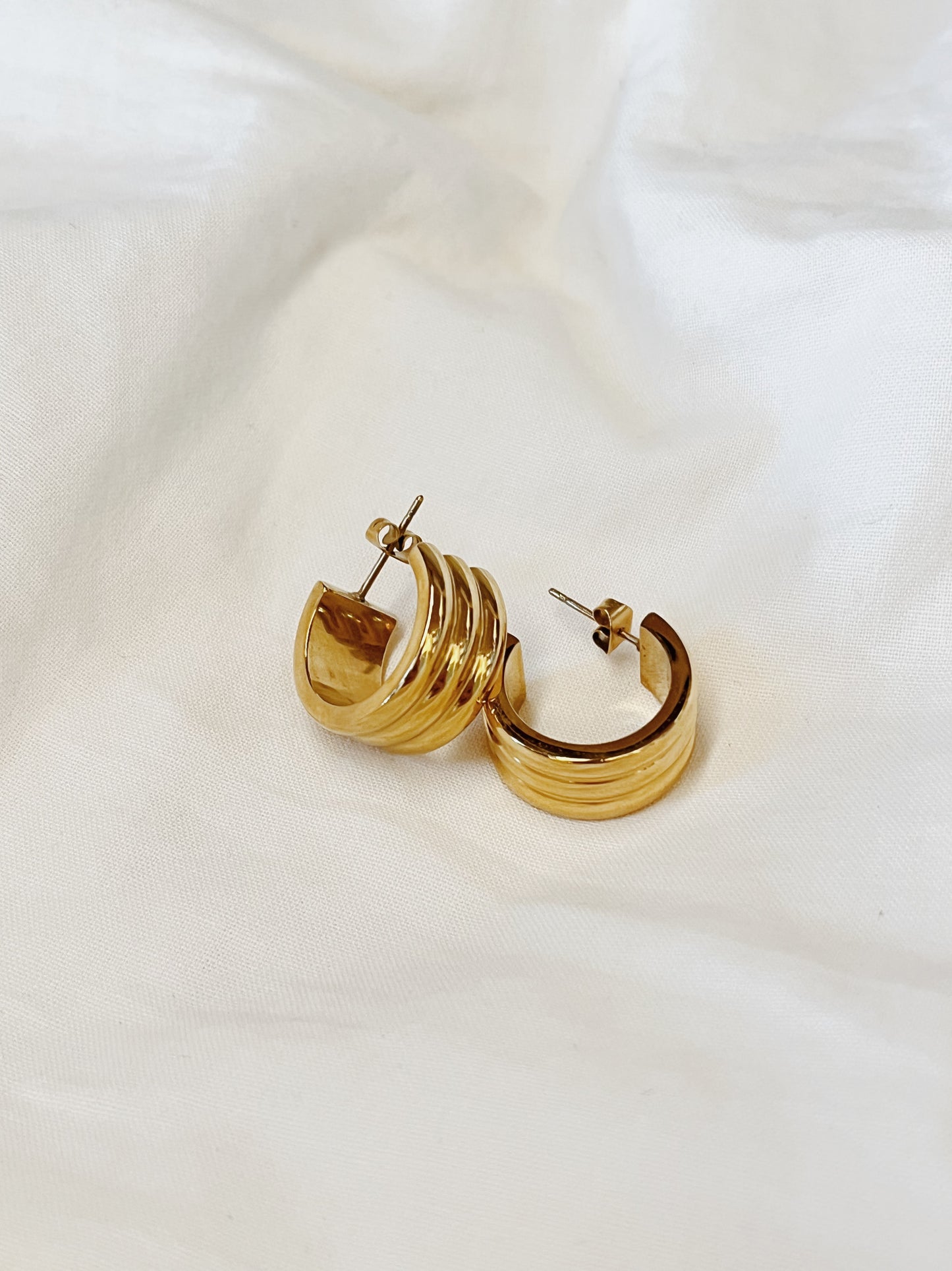 Tactile texture shot showcasing the smooth curves and premium metallic luster of the non-tarnish Lucia gold ribbed hoops.