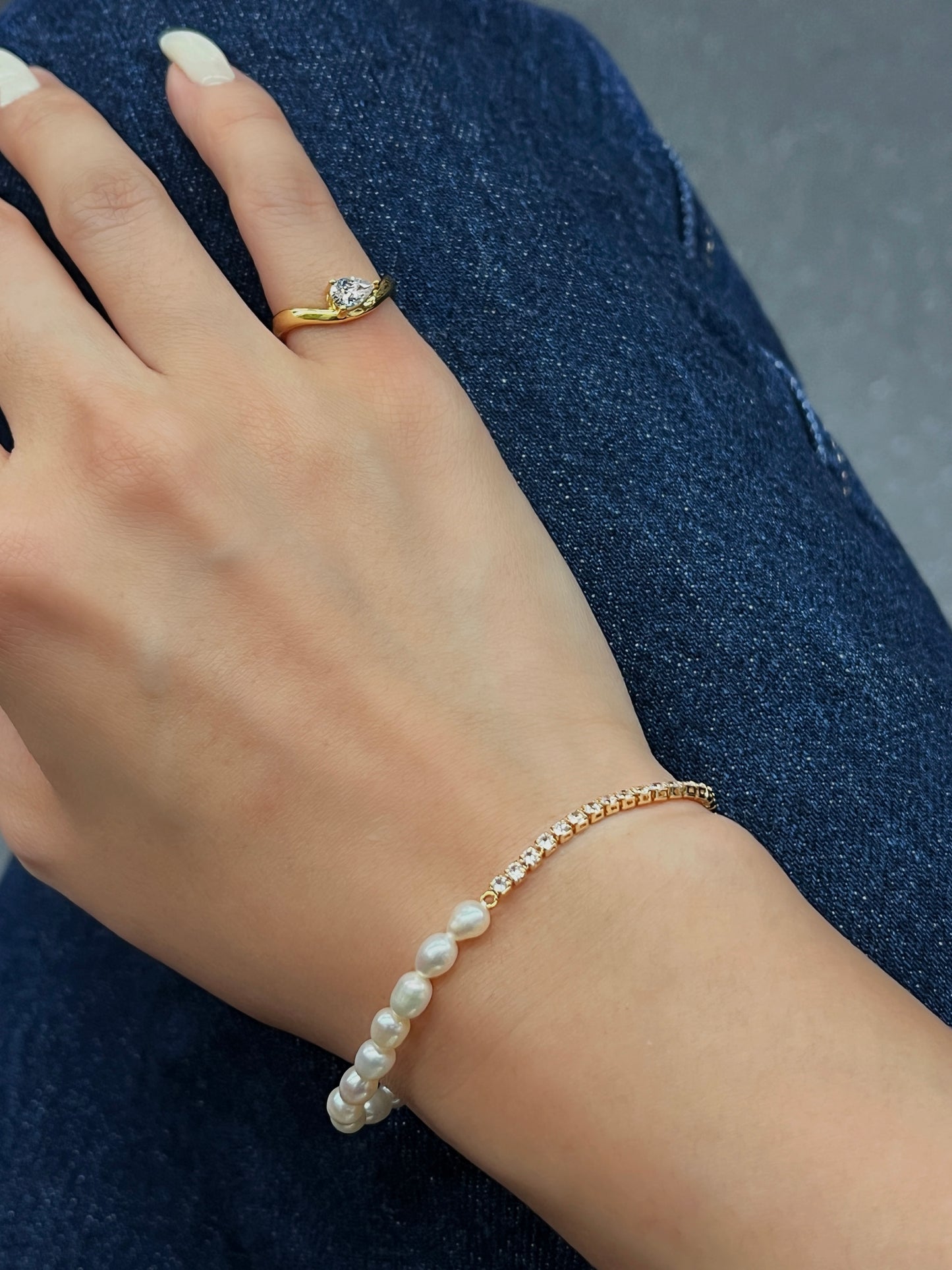 hand shot wearing nova pear solitaire pinky ring resting on blue denim fabric