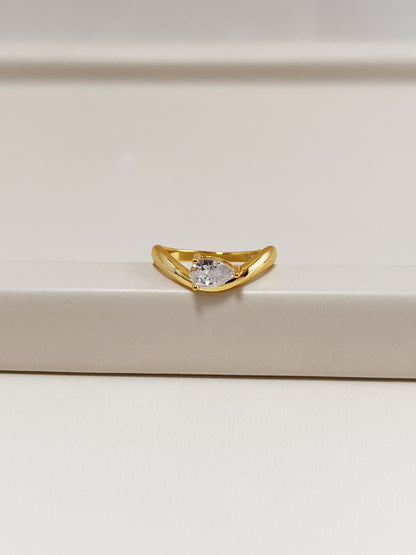 gold nova wave ring with pear moissanite resting on neutral tray