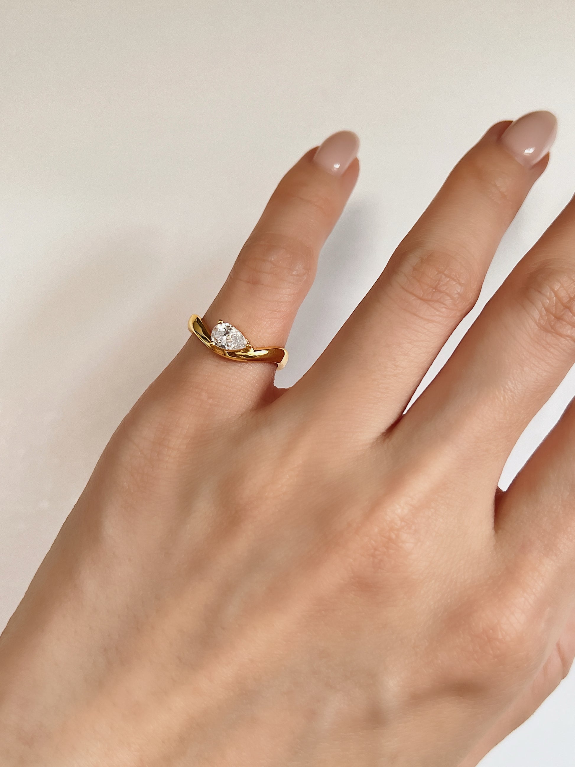 model wearing gold nova pear solitaire wave ring on pinky finger in size 4