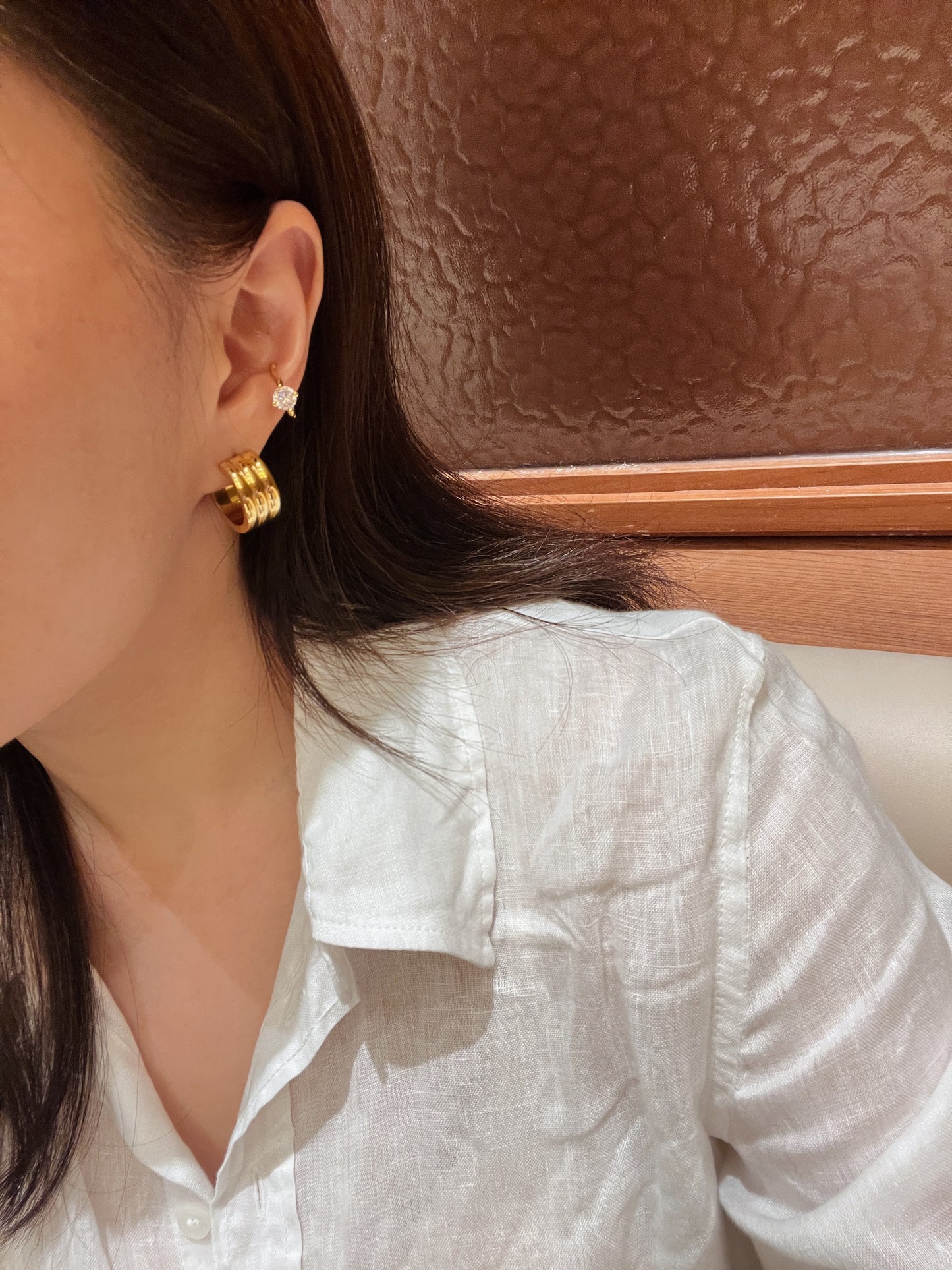 Modern ear curation model shot featuring the Lucia gold ribbed hoops styled seamlessly for an elegant, old-money look.