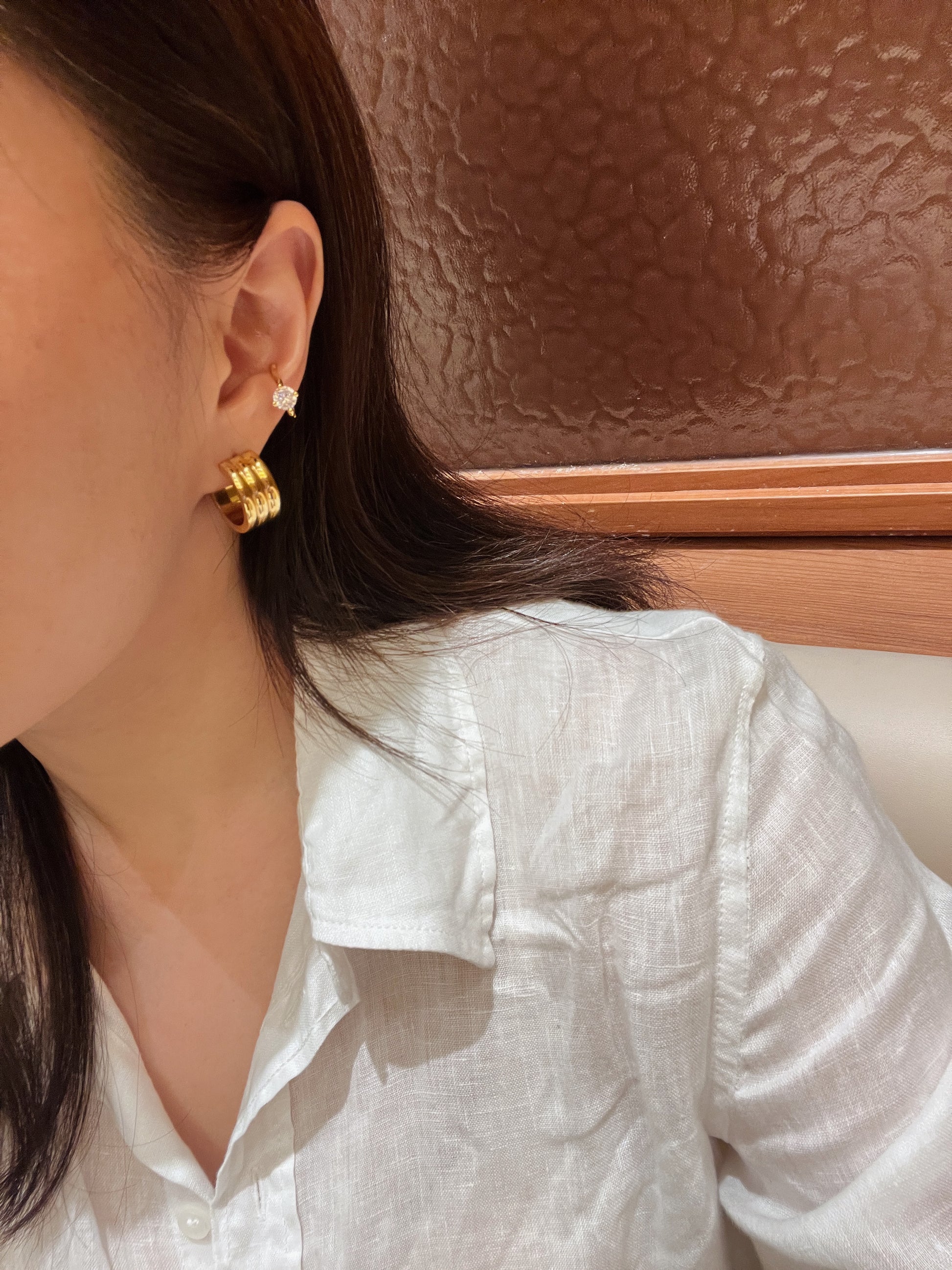 Modern ear curation model shot featuring the Lucia gold ribbed hoops styled seamlessly for an elegant, old-money look.