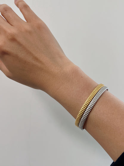 Close-up of a model wearing the gold vermeil stacking cuff alongside a silver variant, showcasing how the jewelry comfortably hugs the lower wrist.