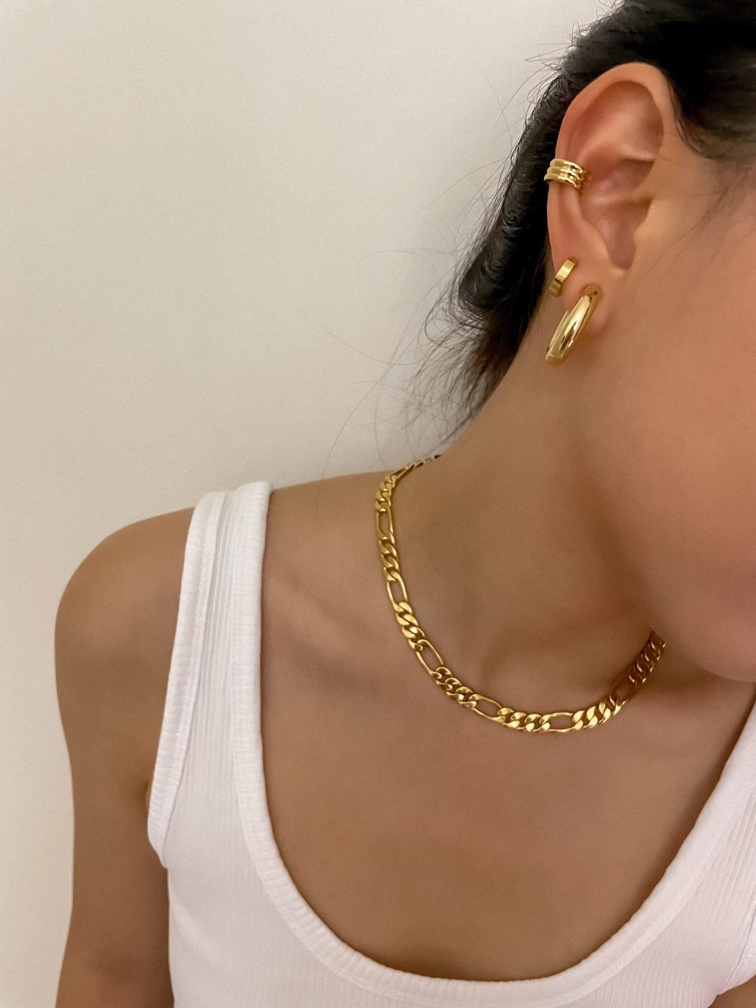 Close up model portrait wearing a white tank top paired with high shine minimal clip jewelry