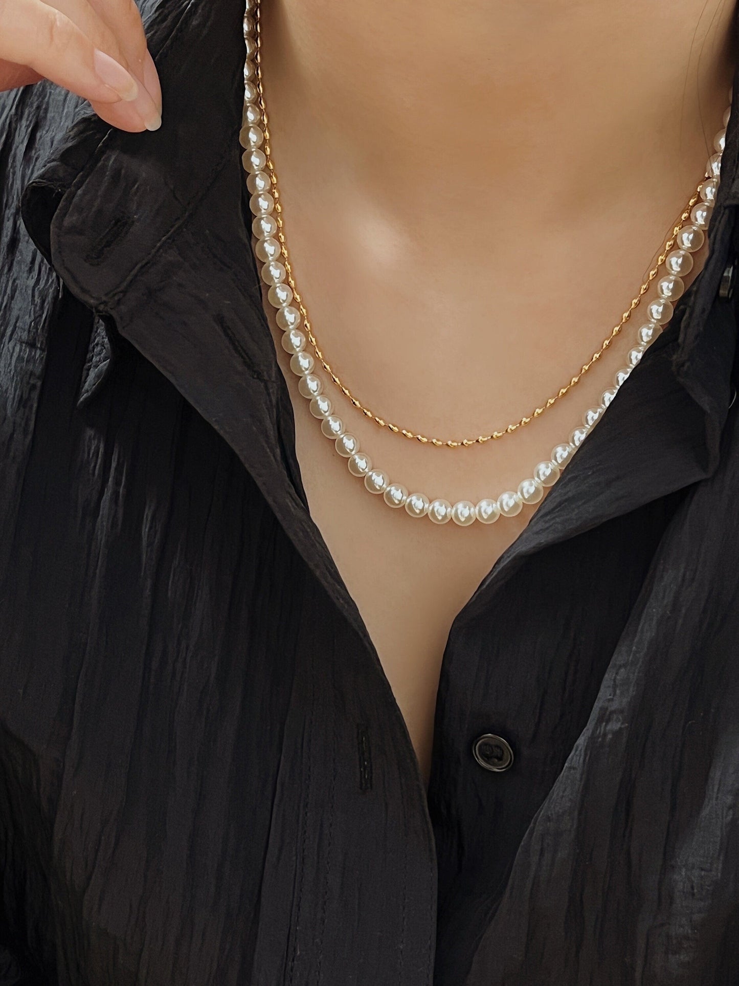 Close up lifestyle view of a model wearing the Livia beaded choker layered perfectly above a classic pearl necklace