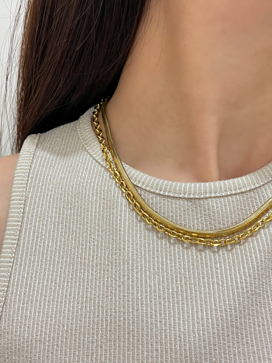 Close up lookbook profile of a model wearing the Trixie cable chain layered elegantly with a flat gold herringbone necklace