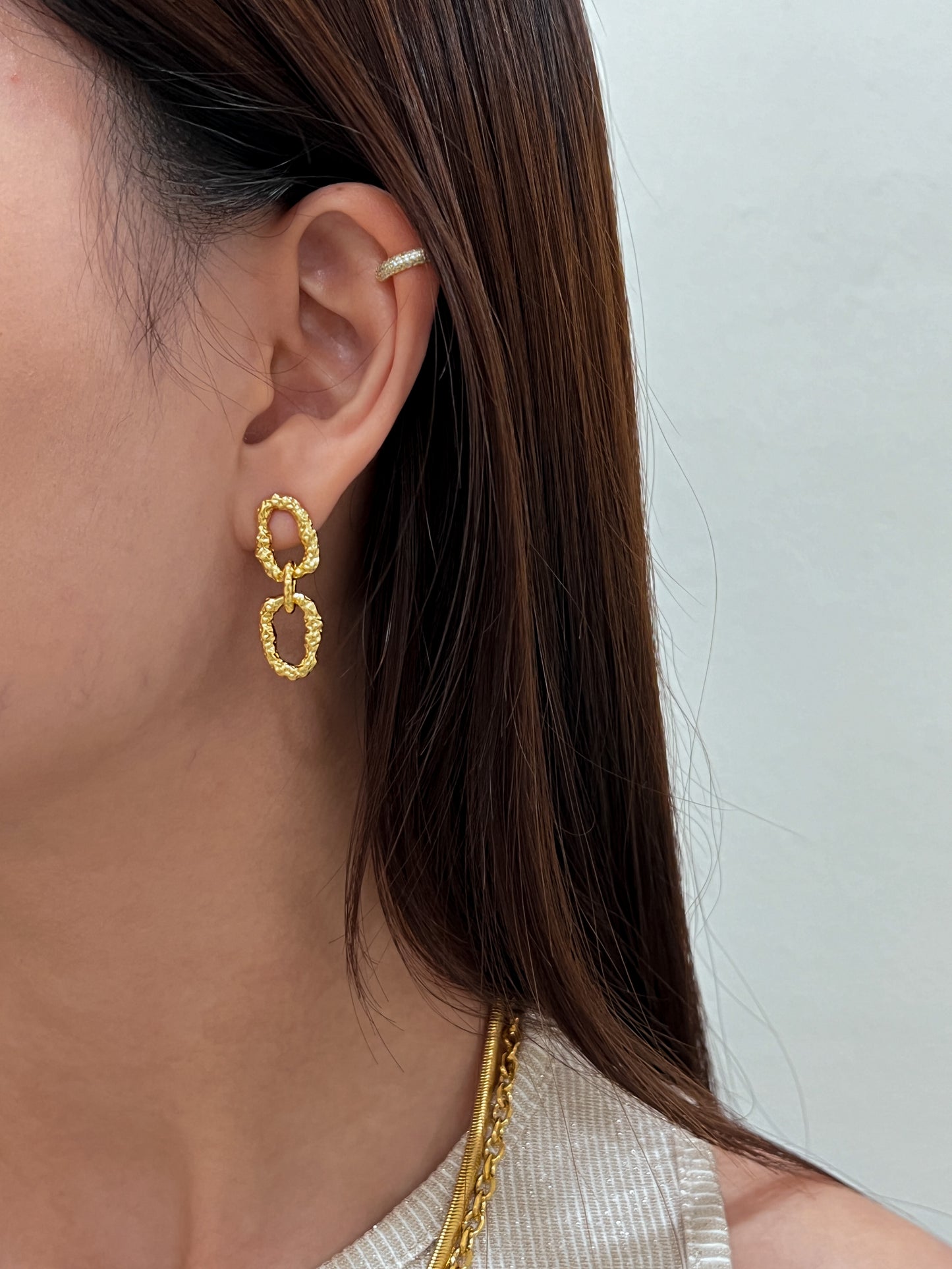 Slicked back hairstyle lookbook feature highlighting a structural gold unrefined fluid link earring drop