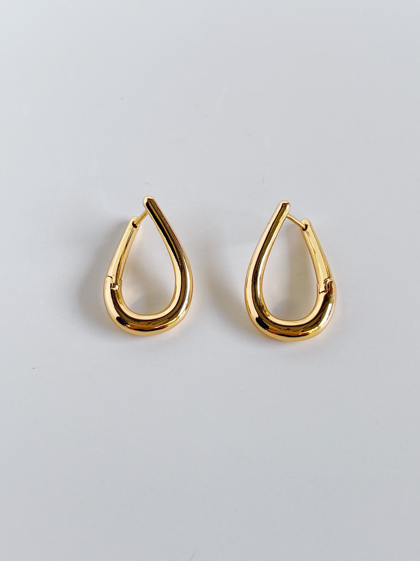 Top-down view of the irregular teardrop silhouette of Ania gold earrings.