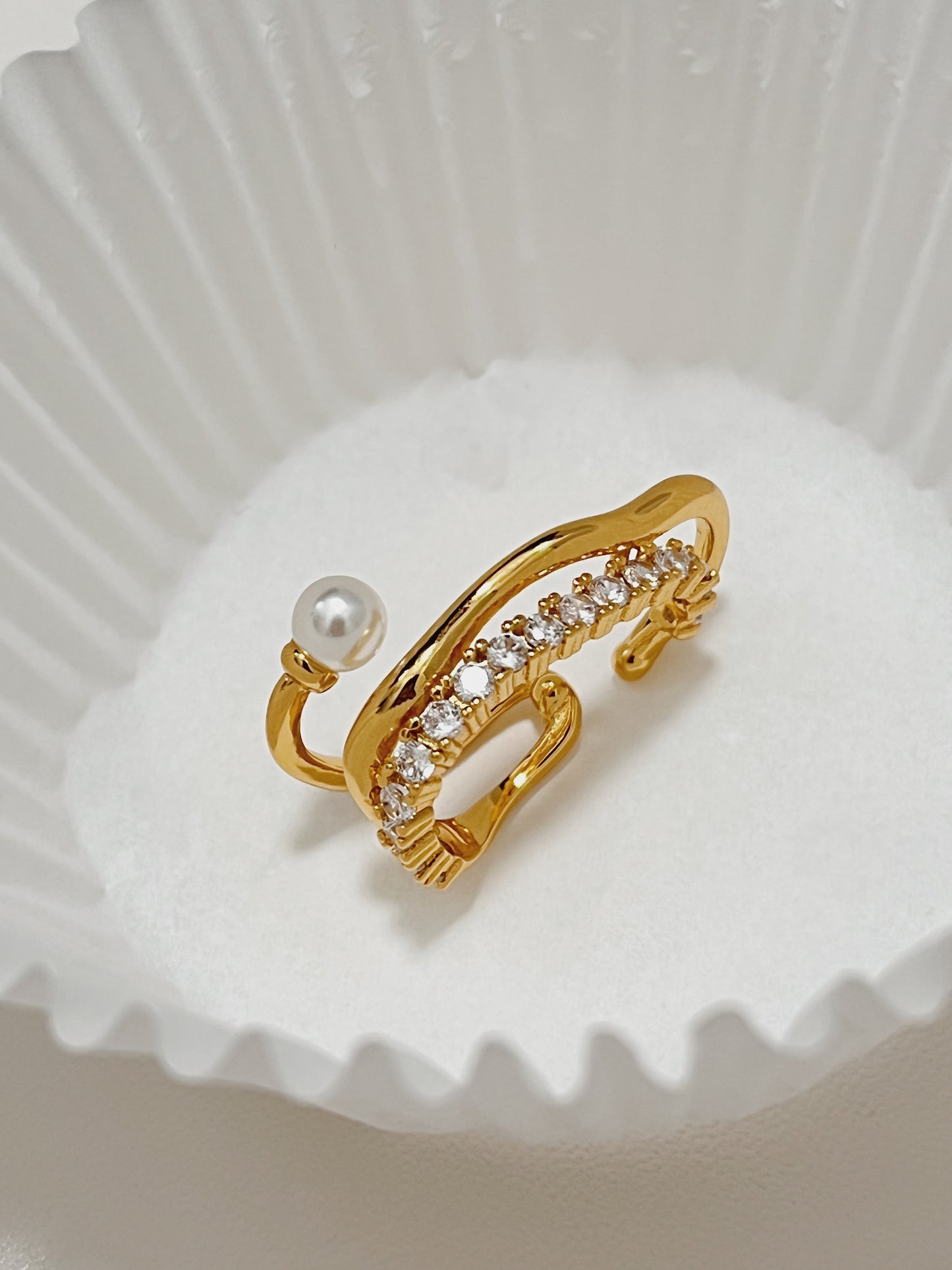 Close-up photograph of the ornate Cassidy Gold Cuff Earring with a genuine round freshwater pearl and pave cubic zirconia, displaying its timeless beauty and high-end finish.