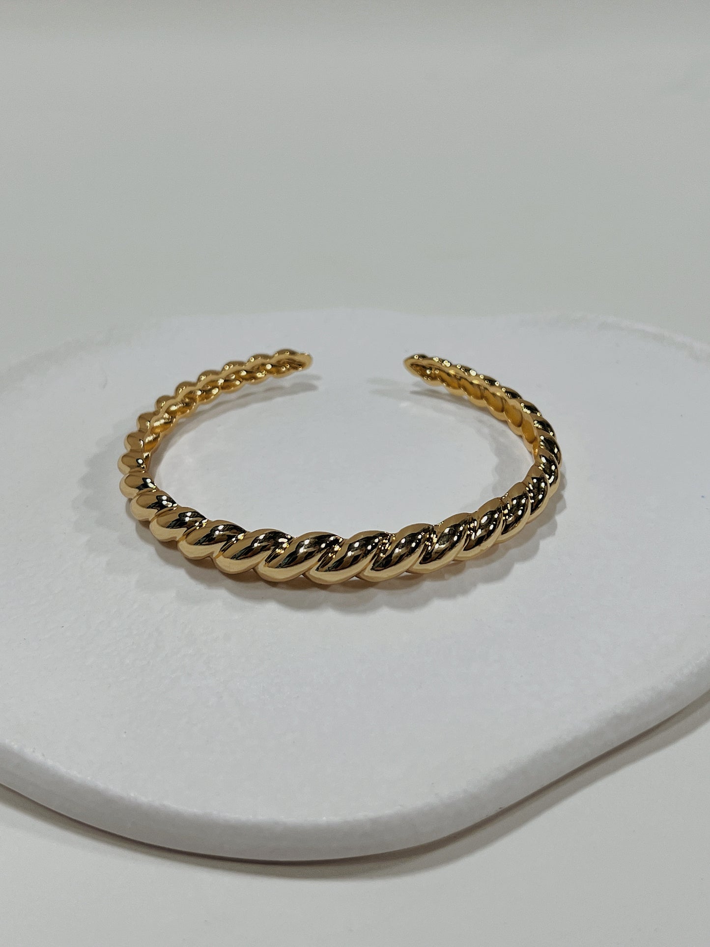 Macro view focusing on the distinct twisted uneven surface texture of the Paris Croissant 18K gold PVD cuff bangle.