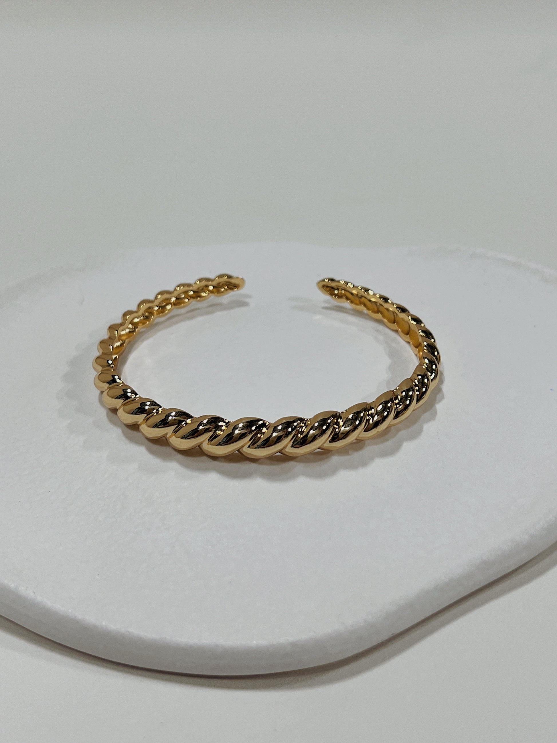 Macro view focusing on the distinct twisted uneven surface texture of the Paris Croissant 18K gold PVD cuff bangle.