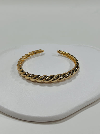 Macro view focusing on the distinct twisted uneven surface texture of the Paris Croissant 18K gold PVD cuff bangle.
