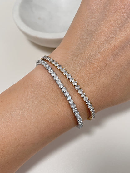 Close-up of a stacked wrist look featuring a gold tennis bracelet and silver tennis bracelet.