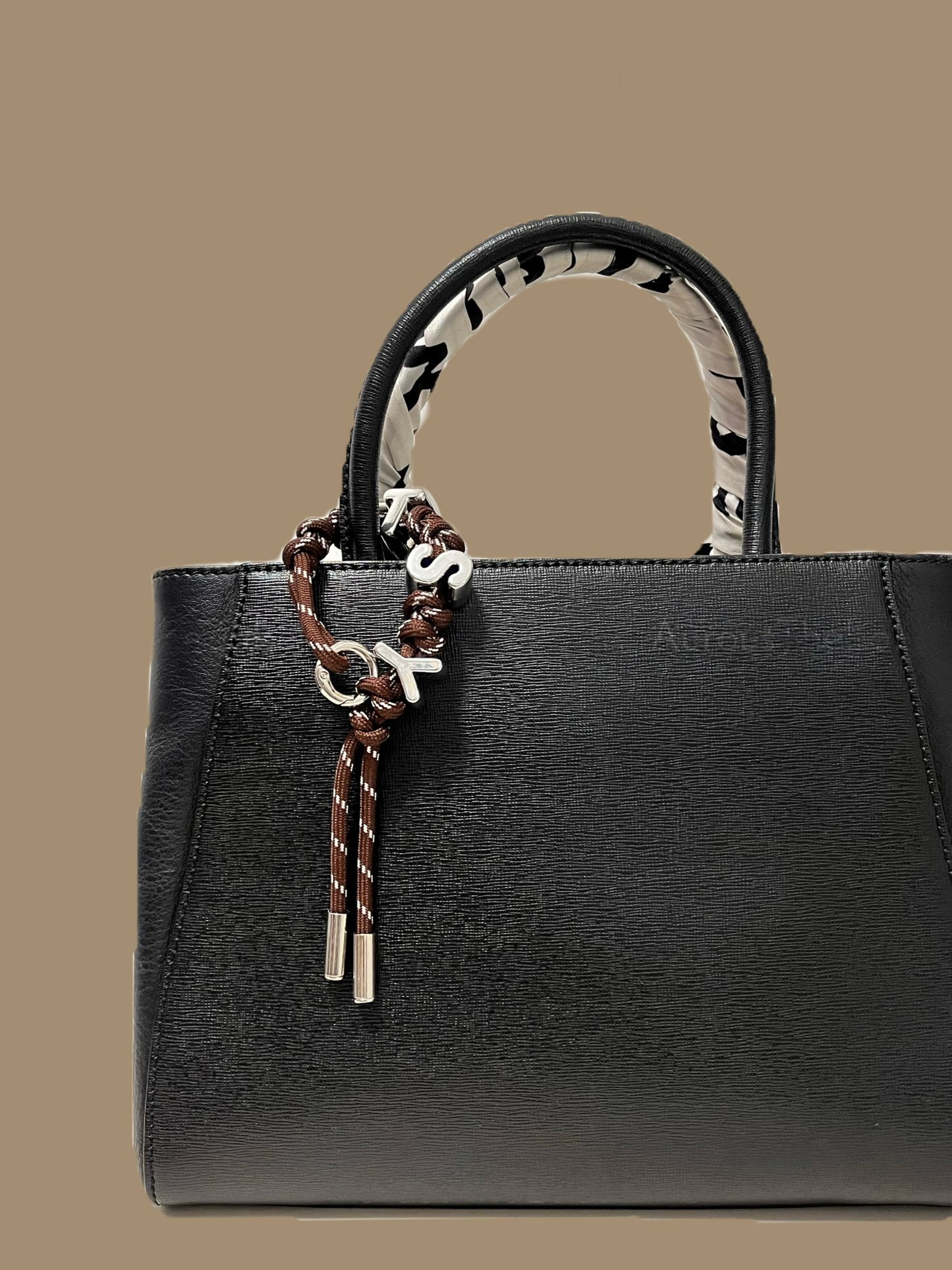 Personalized handbag charm styled on a black leather luxury tote bag.
