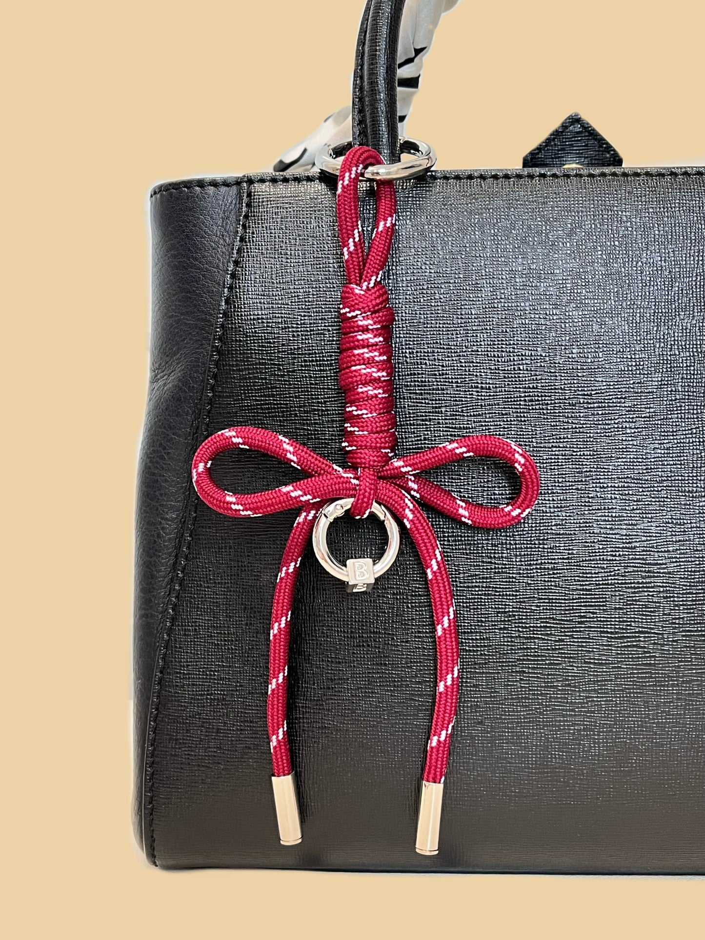 Close up perspective of a hand knotted paracord bow bag charm showing the structured utility weave pattern