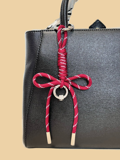 Close up perspective of a hand knotted paracord bow bag charm showing the structured utility weave pattern