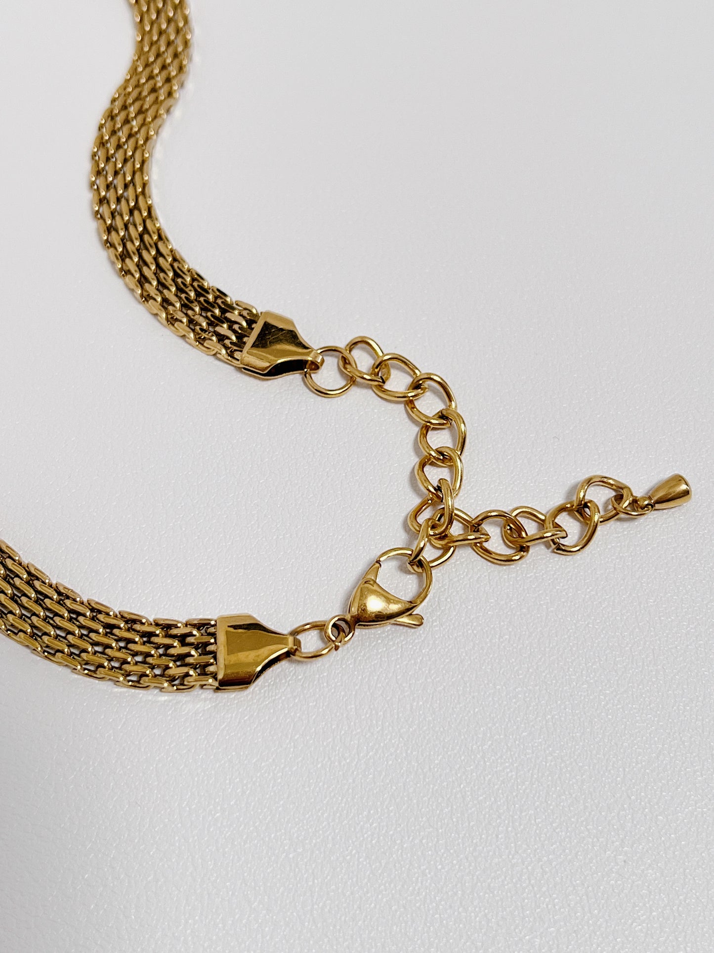 Polished triangular endcaps and lobster clasp mechanism on a wide flat gold mesh chain necklace