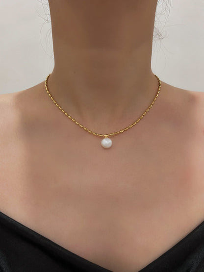 Neck profile of a woman showcasing an elegant freshwater pearl pendant choker against a clean studio backdrop