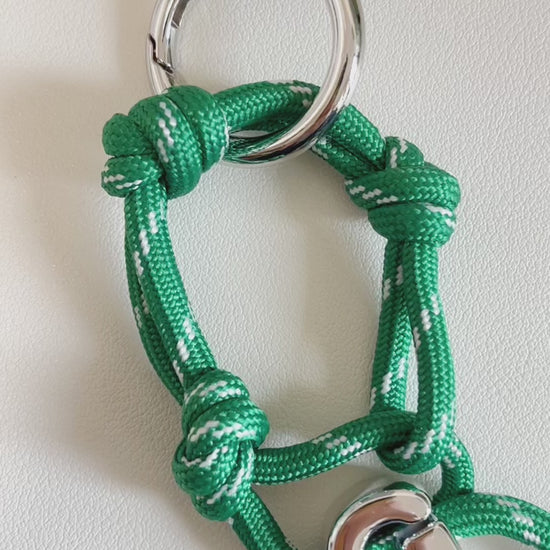 Oversized chrome initial letter G bead suspended from a green and white patterned tactical cord loop
