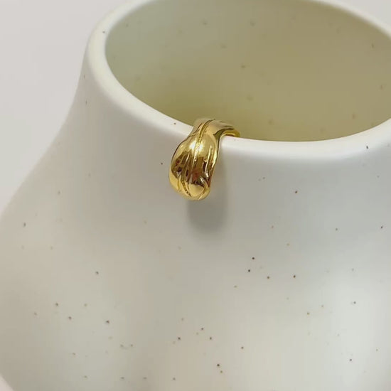 gold ear cuff on a ceramic cup