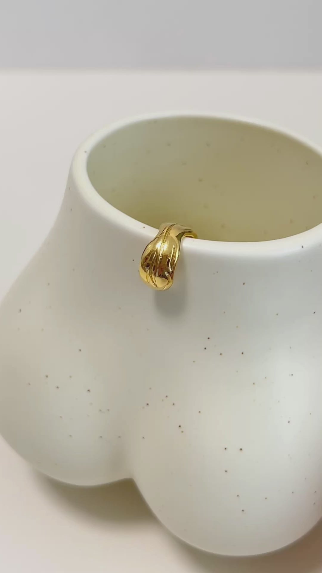 gold ear cuff on a ceramic cup