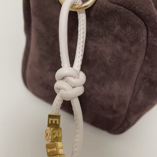 Personalized bag charm on dark brown suede tote.