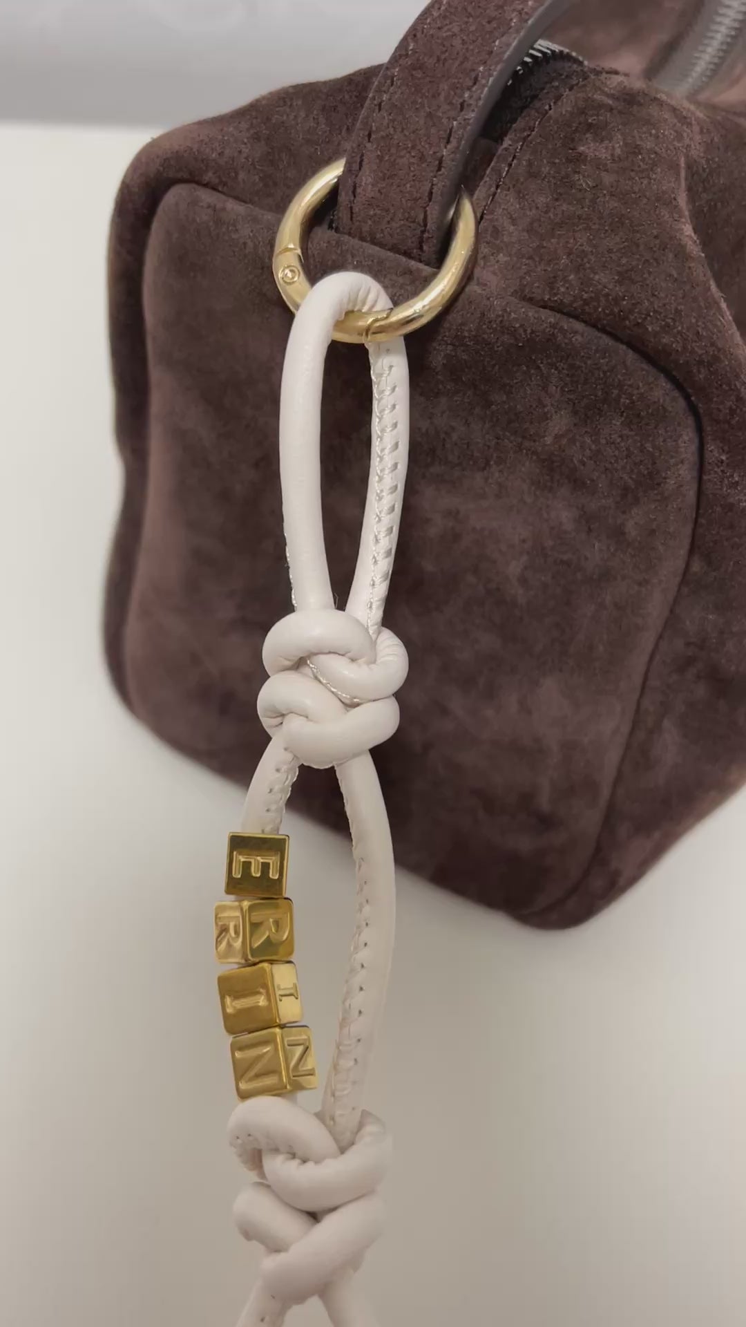 Personalized bag charm on dark brown suede tote.