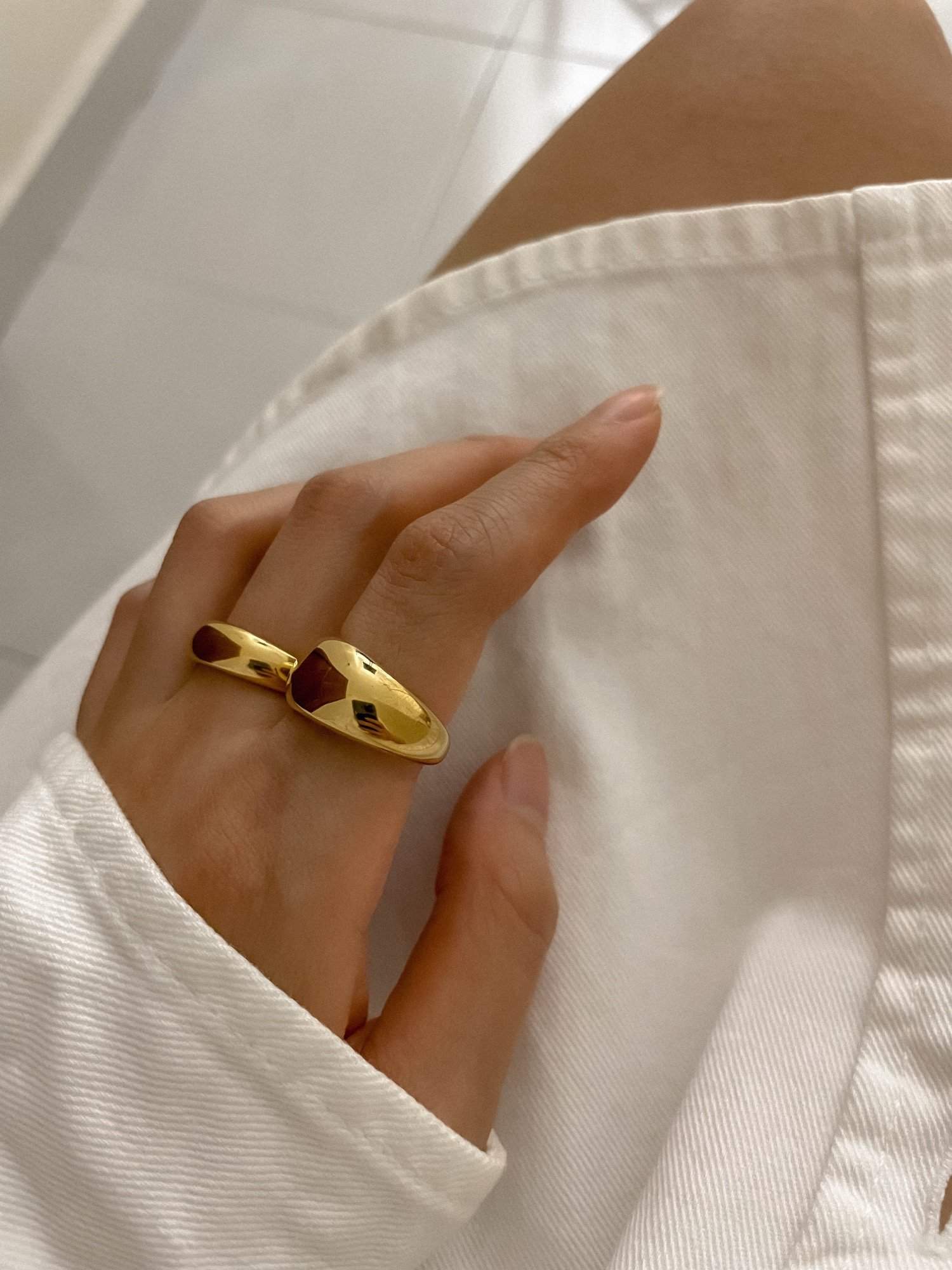 Modern stack featuring slim and thick gold dome rings on a hand model
