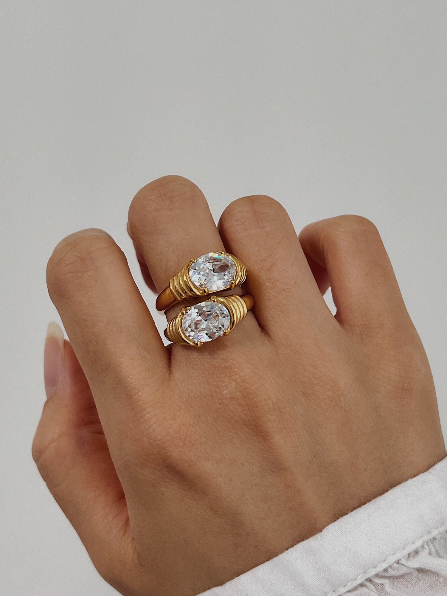 Modern jewelry stack featuring gold sparkle rings on hand