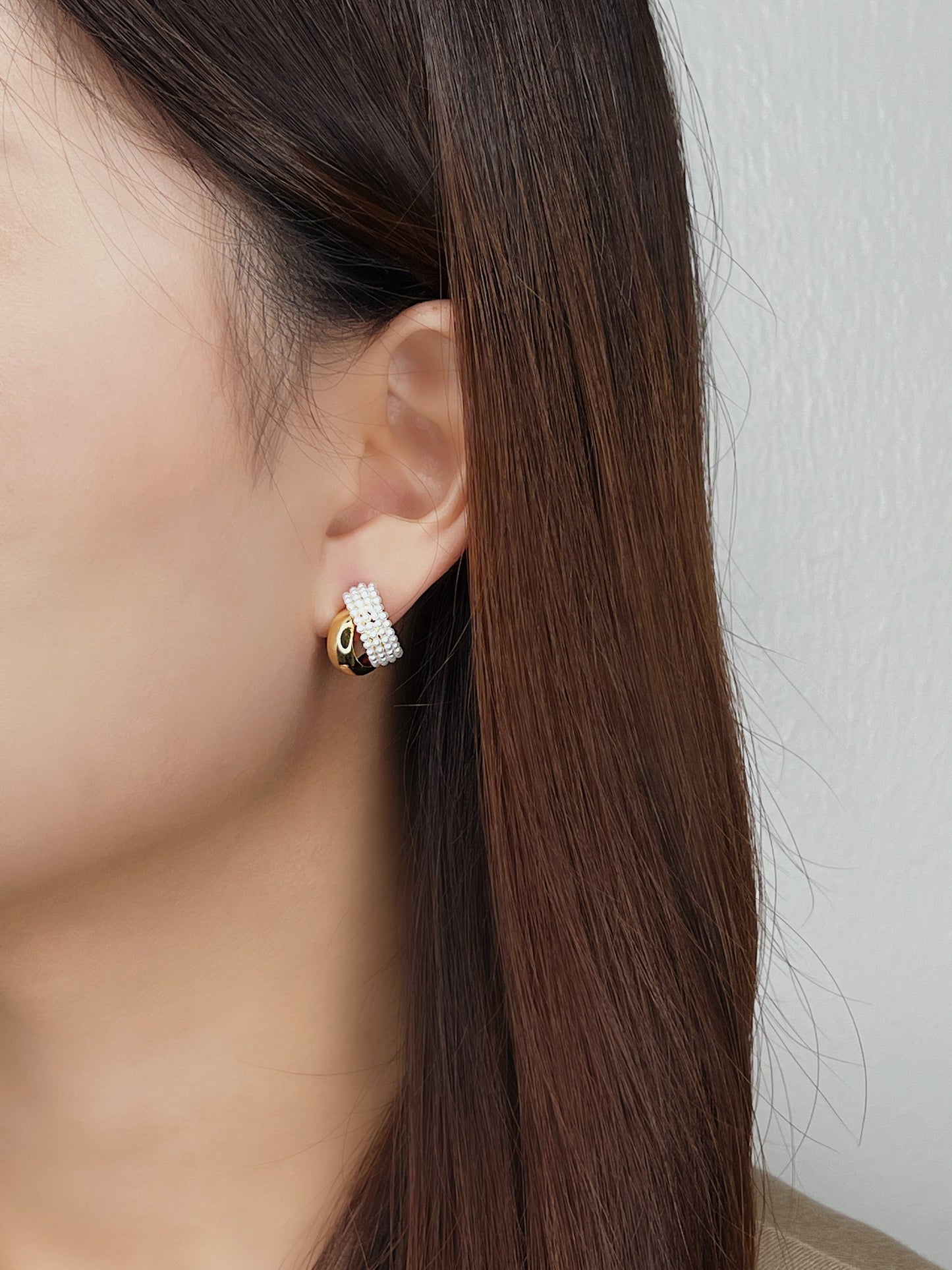Editorial style jewellery lookbook photo highlighting smooth gold metal curves beside dark hair