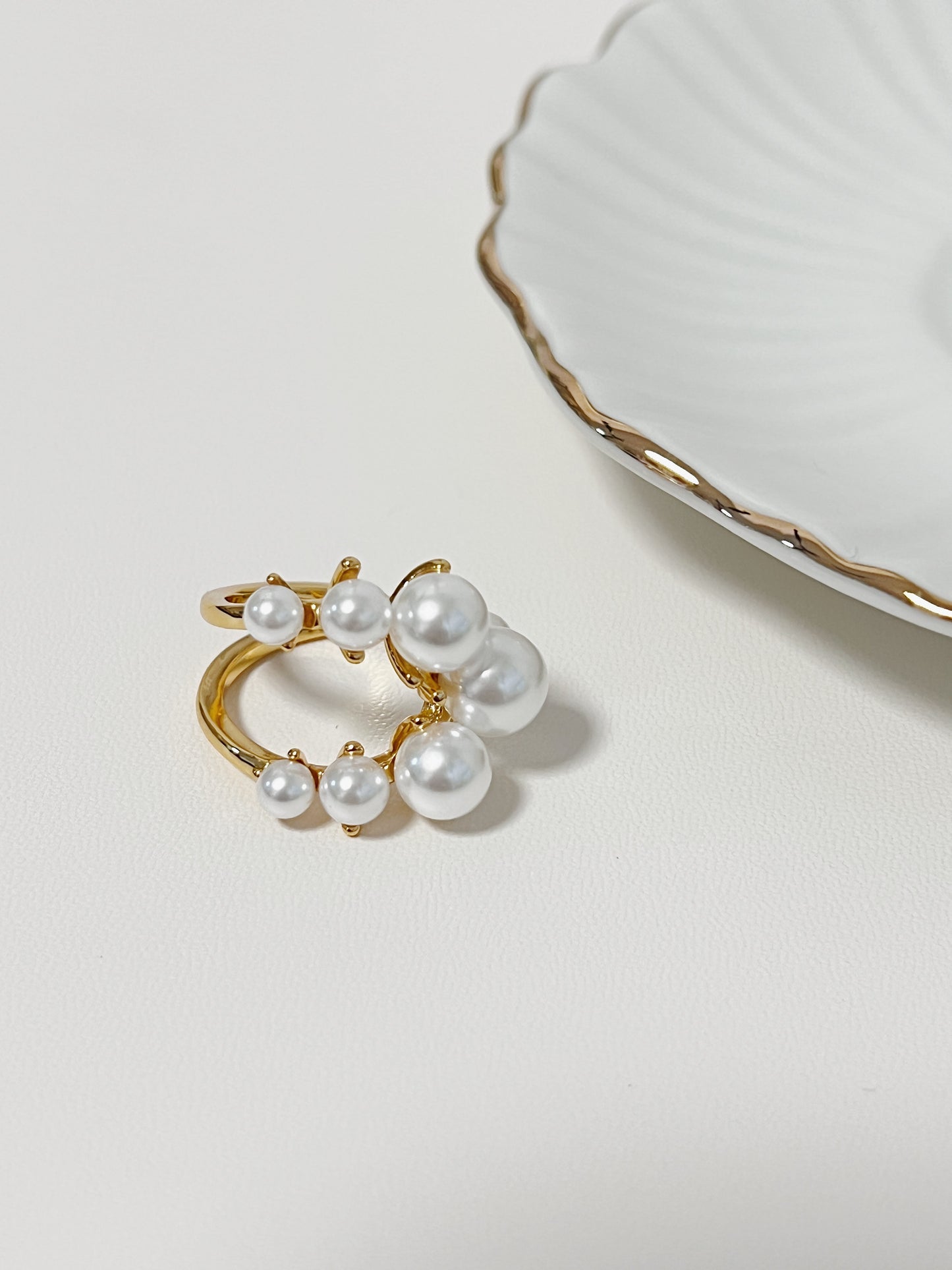 Architectural liquid gold pearl ring on a clean display surface