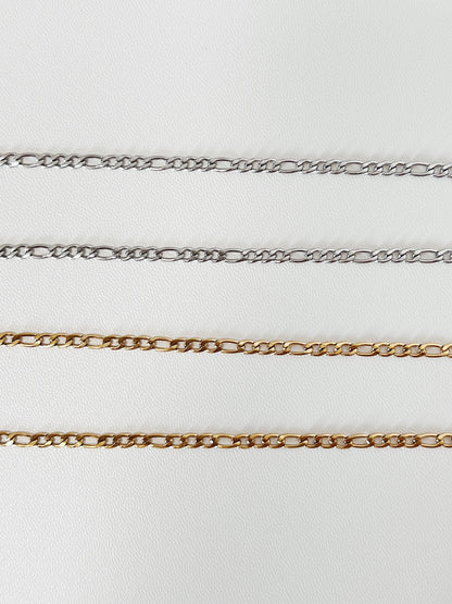 A straight, linear laydown of the gold and silver Rhea Figaro chain, emphasizing the geometric precision and consistent spacing of the Italian link structure.