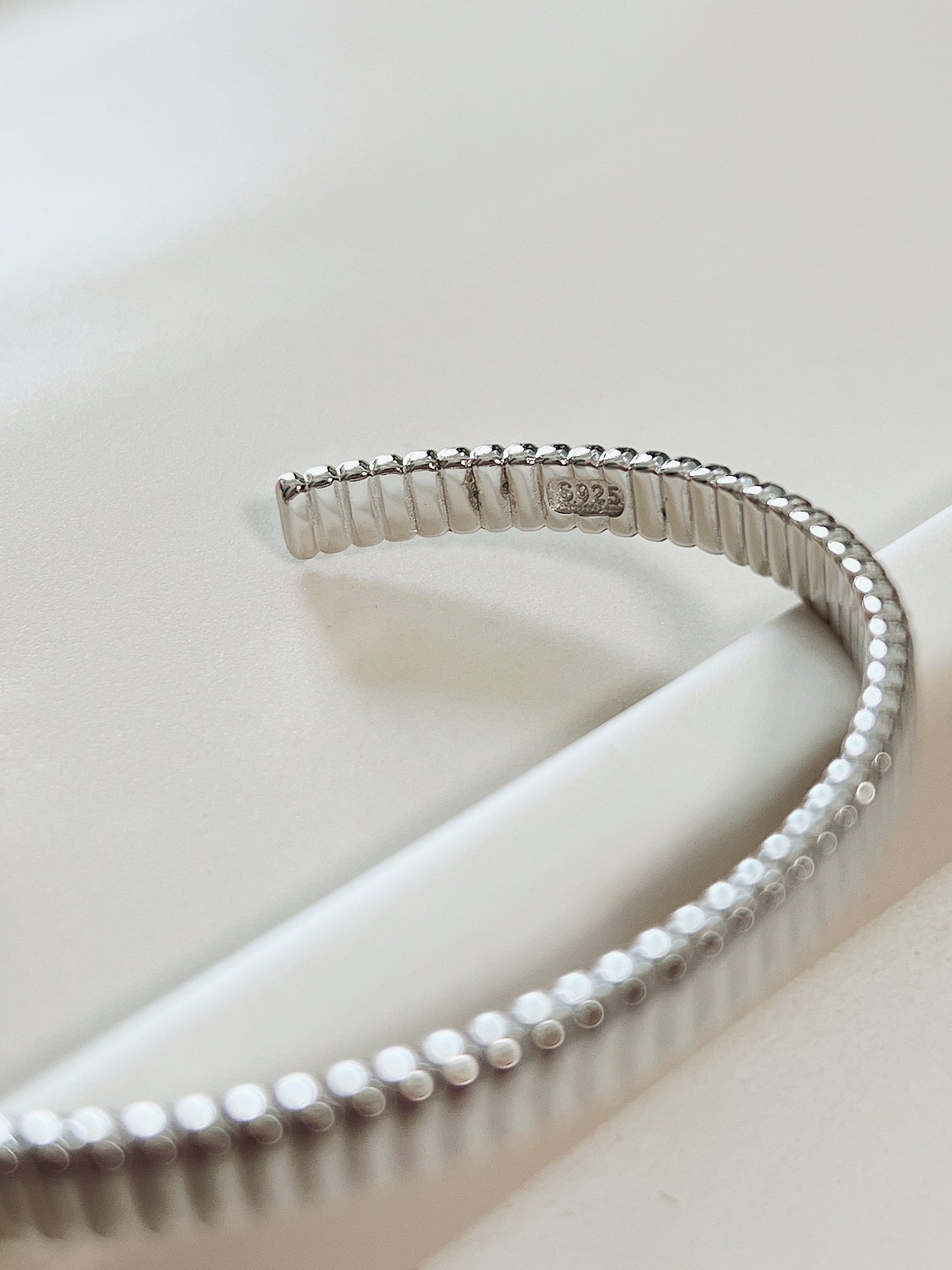 Macro product close-up highlighting the official s925 authenticity hallmark stamped on the smooth inner wall of the silver ribbed open cuff.