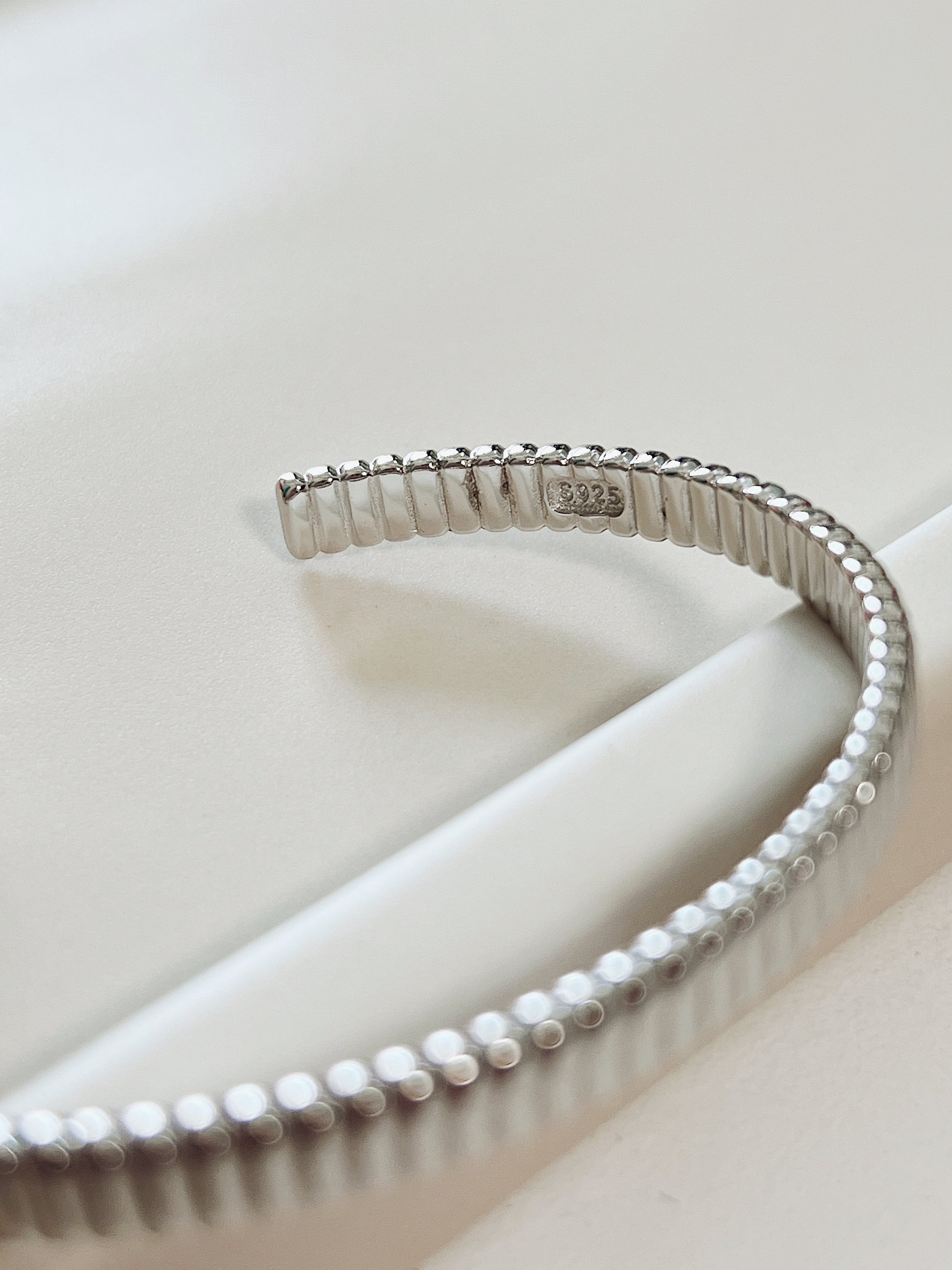 Macro product close-up highlighting the official s925 authenticity hallmark stamped on the smooth inner wall of the silver ribbed open cuff.