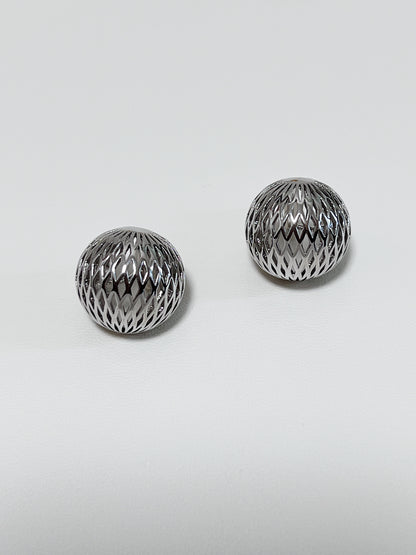 Minimalist flat lay of cool silver openwork clip-on earrings for versatile capsule wardrobe styling.
