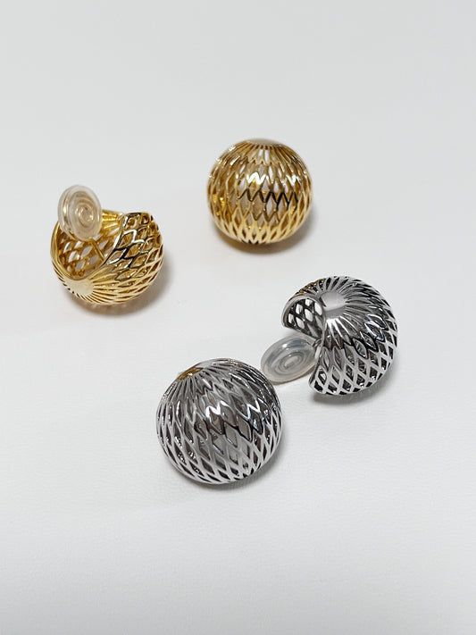 High-shine 14K gold plating across the openwork woven lattice pattern of a hollow dome clip-on earring on white marble.