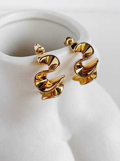 Pair of Isla statement gold hoops on a white display surface