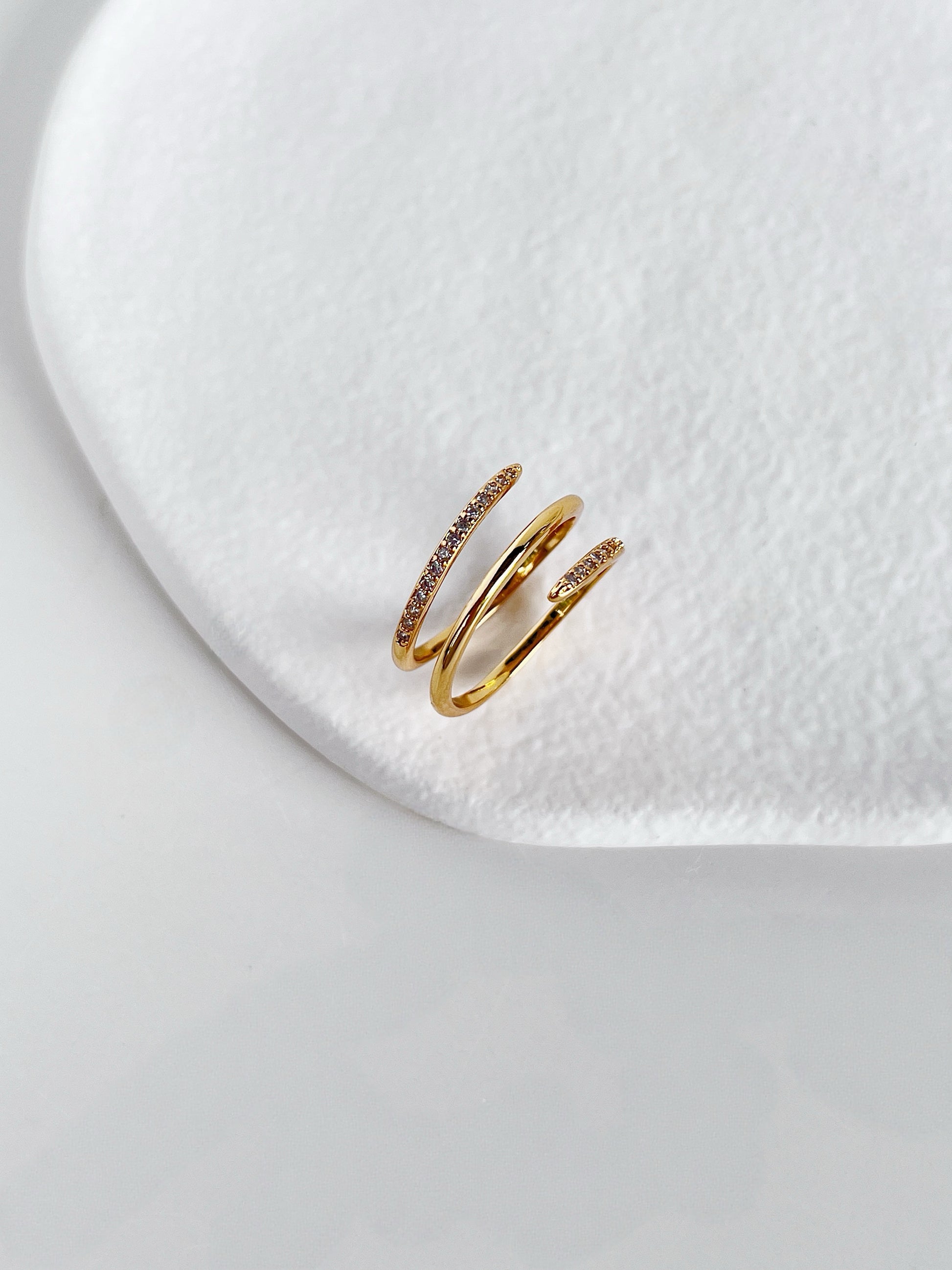 Architectural triple band effect gold ring on white surface