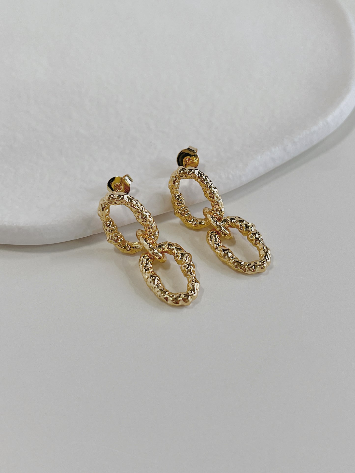 Side profile view of gold textured interlocking link drop earrings highlighting secure post stud closures