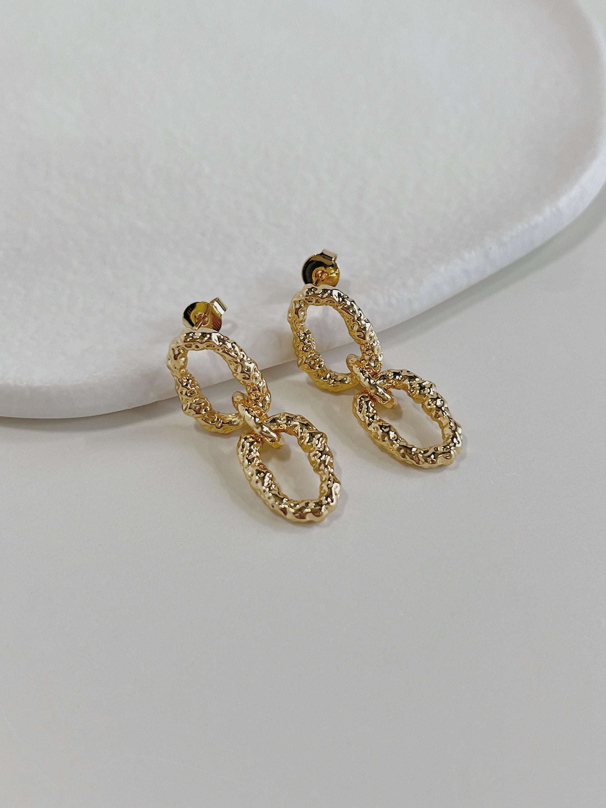 Side profile view of gold textured interlocking link drop earrings highlighting secure post stud closures