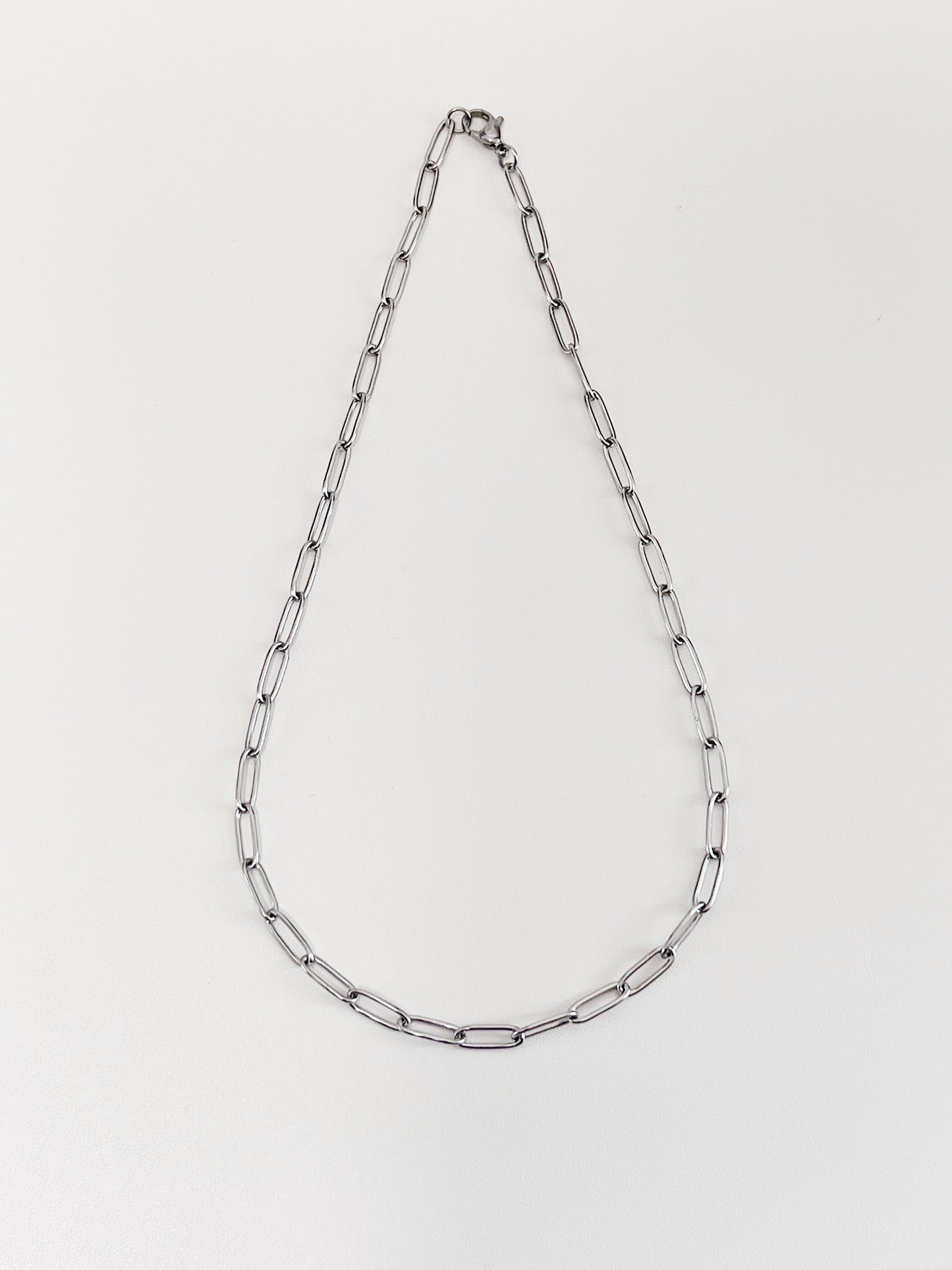 The 4mm thick silver paperclip link necklet laid out symmetrically to display its airy minimalist structural framework