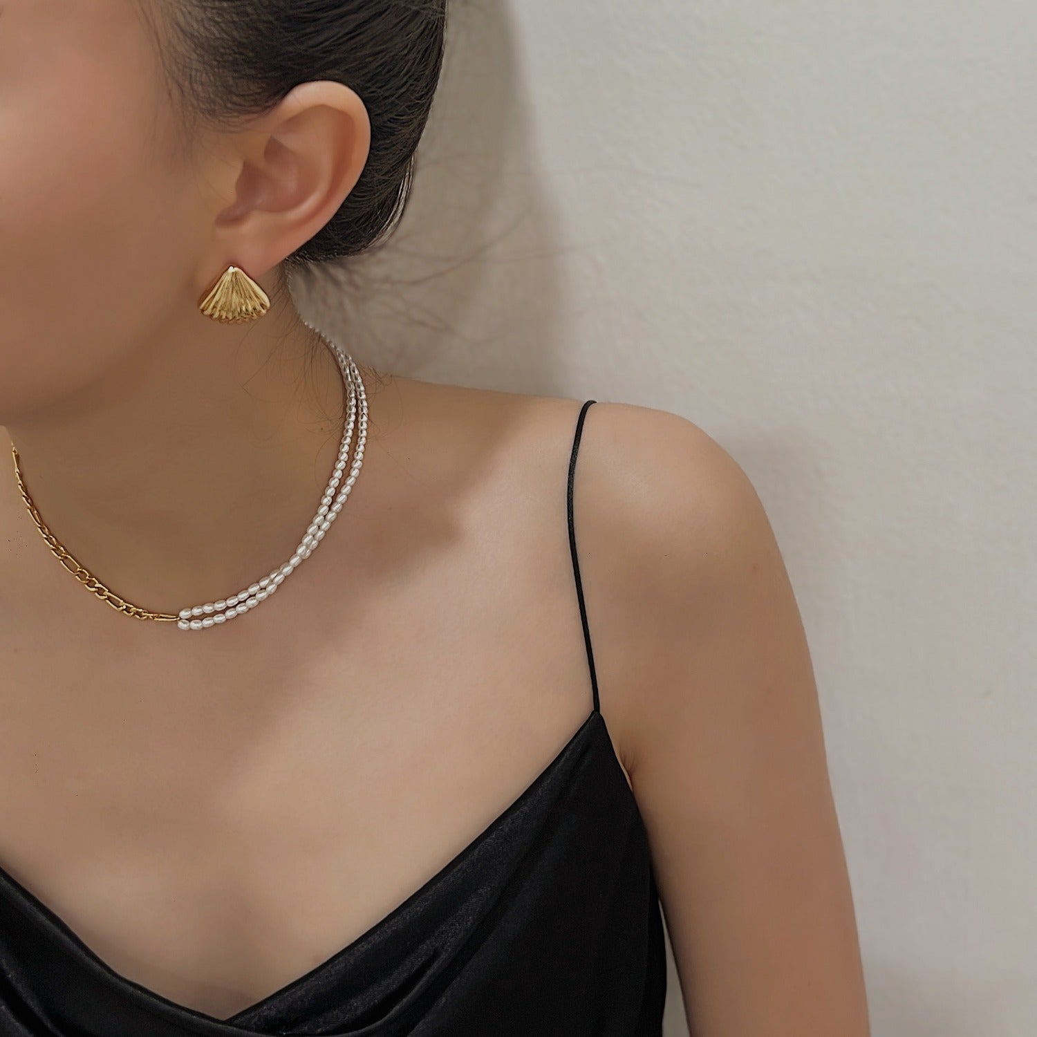 Editorial styling of a mixed texture layered pearl chain necklace on female neck
