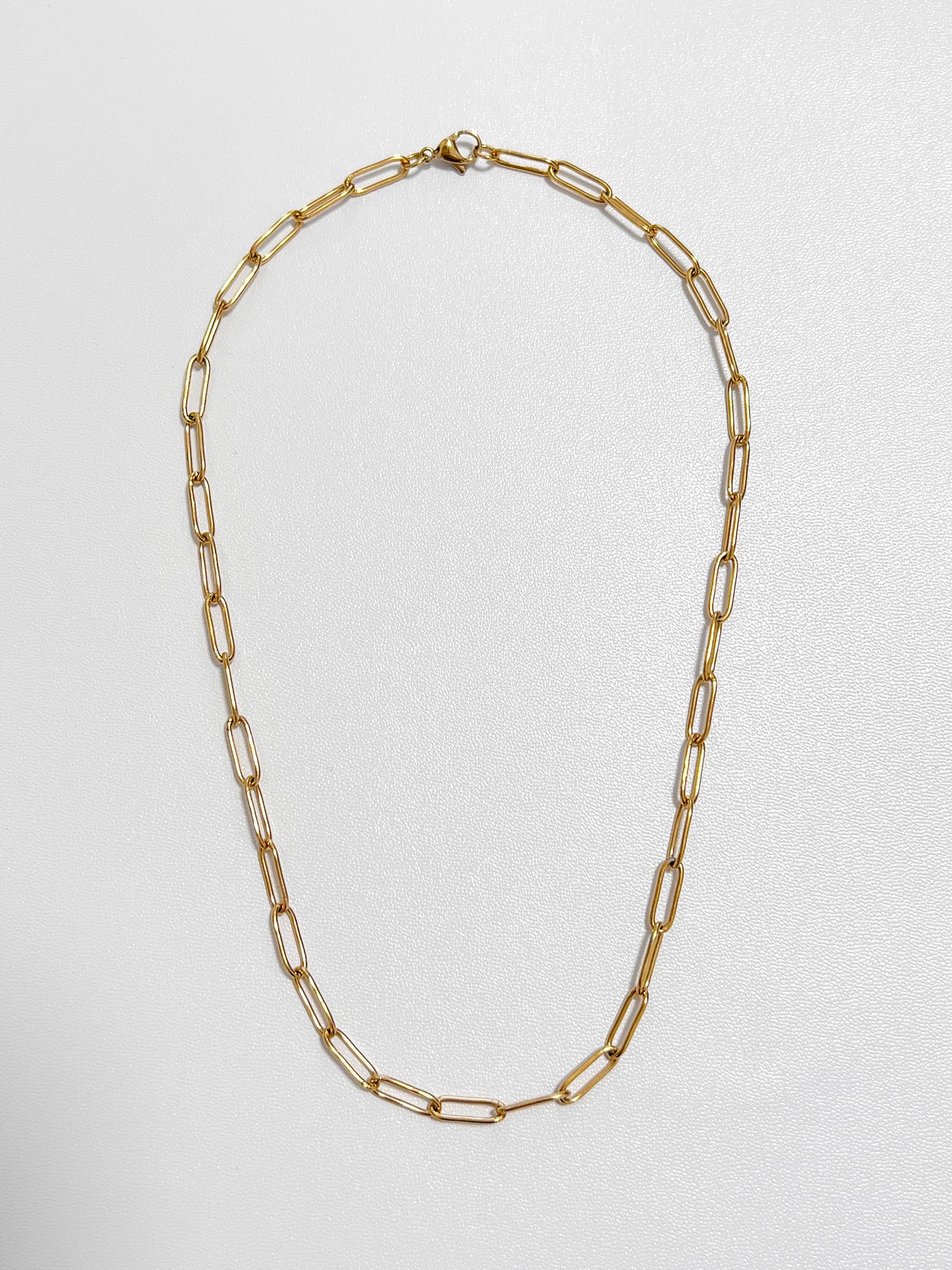 Overhead view of the Sofia paperclip chain necklace highlighting its 4mm flat elongated capsule loop profile on a white display