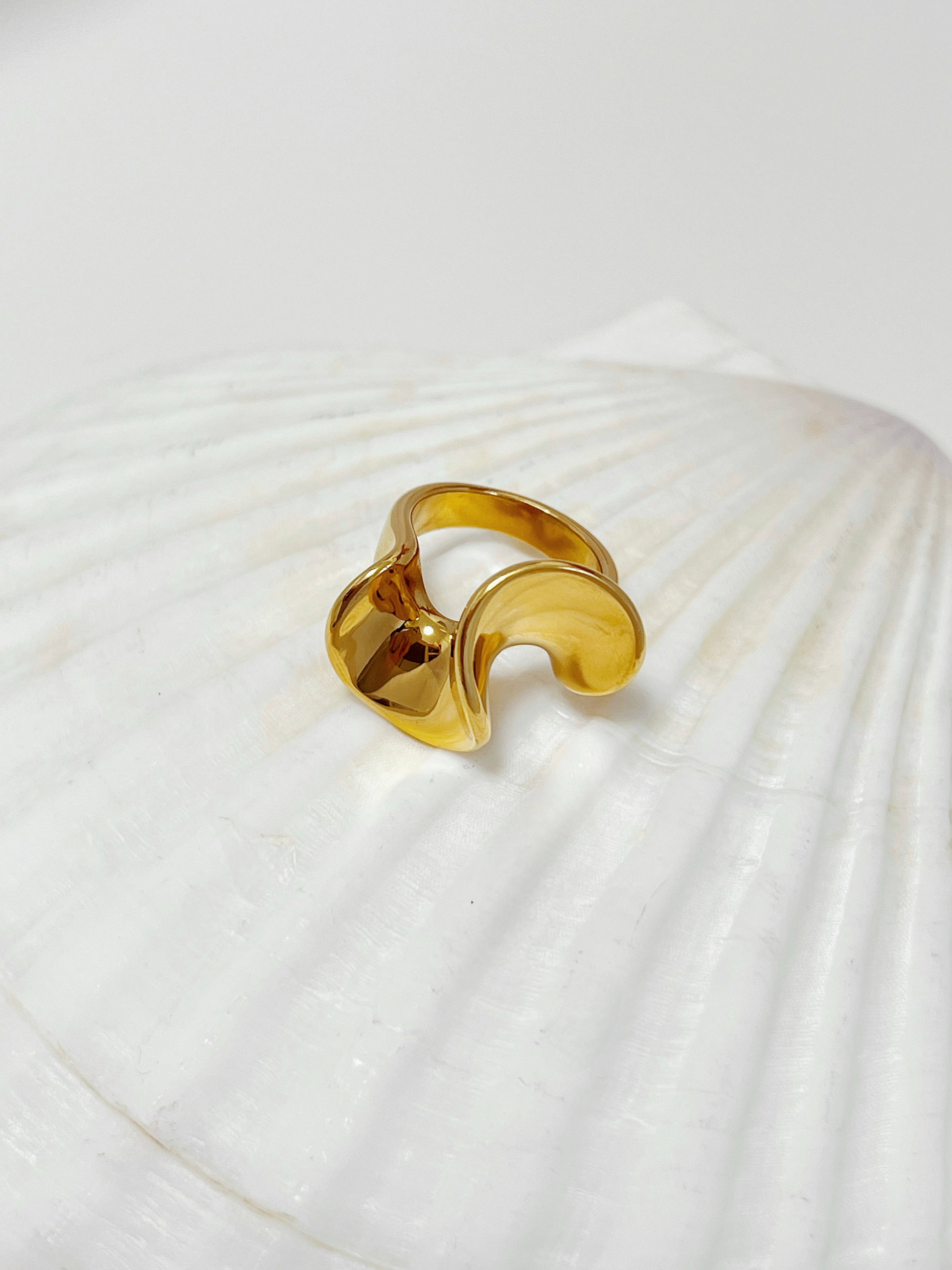 Front view of the unbroken fluid wave curves on the gold statement ring