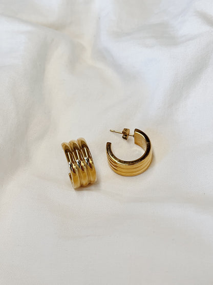 Studio product photograph focusing on the heavy-gold texture and sculptural grooves of the Lucia statement hoop earring.