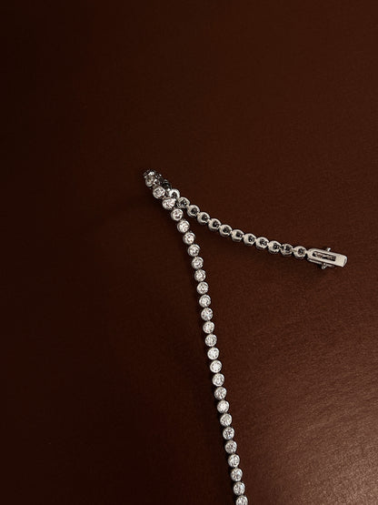 Close-up view of the double-latch box clasp closure and smooth bezel stone settings of a rhodium silver tennis bracelet.