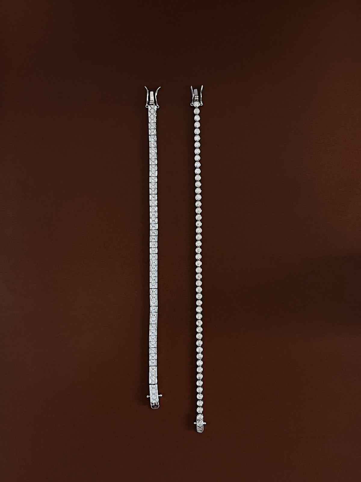 full-length flatlay comparing a straight square-cut tennis bracelet alongside a round bezel-set tennis bracelet on an espresso background.