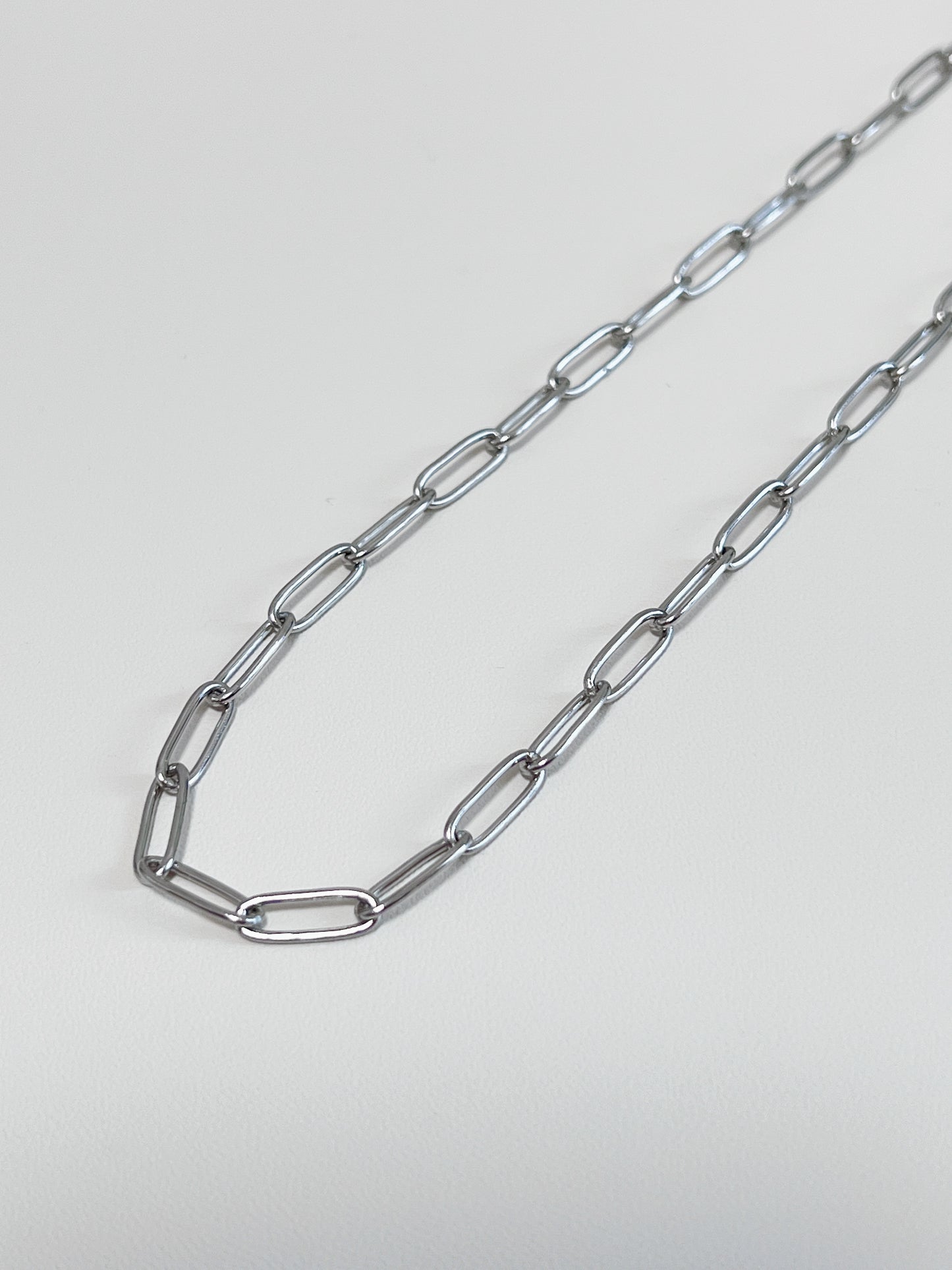 Still life presentation highlighting the supple fabric-like drape of a contemporary luxury paperclip collar chain